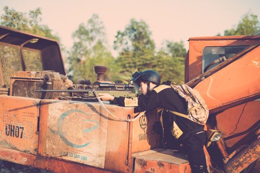 Person engaging in realistic outdoor play with a toy sniper rifle on industrial machinery.
