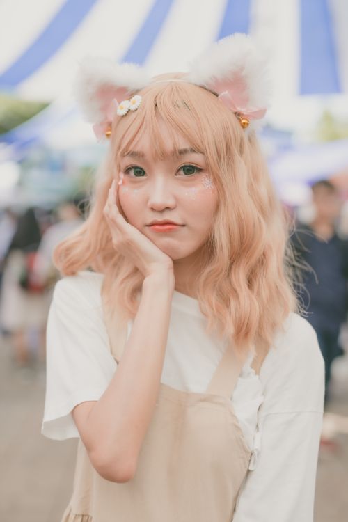 Free A cute cosplayer posing outdoors wearing a kitty headband and beige costume. Stock Photo