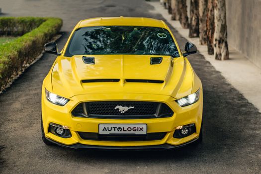 Front view of a yellow Ford Mustang sports car parked on a city street.