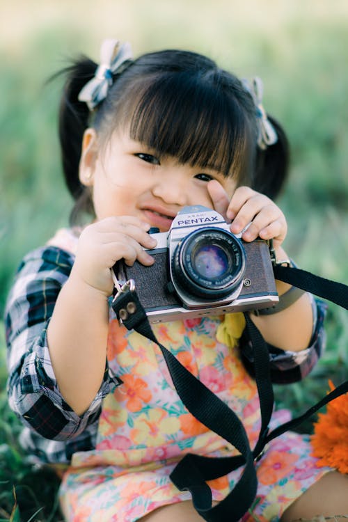 A Girl Holding a Camera with a Strap