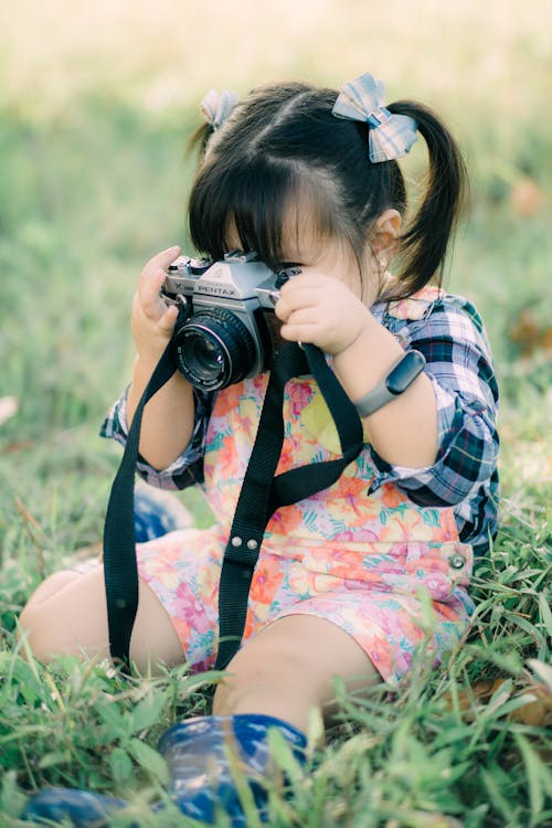 A Cute Girl Sitting on the Grass while Taking Photo