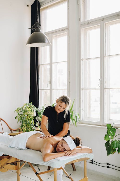 Photo of a Topless Woman Getting a Back Massage from a Masseuse