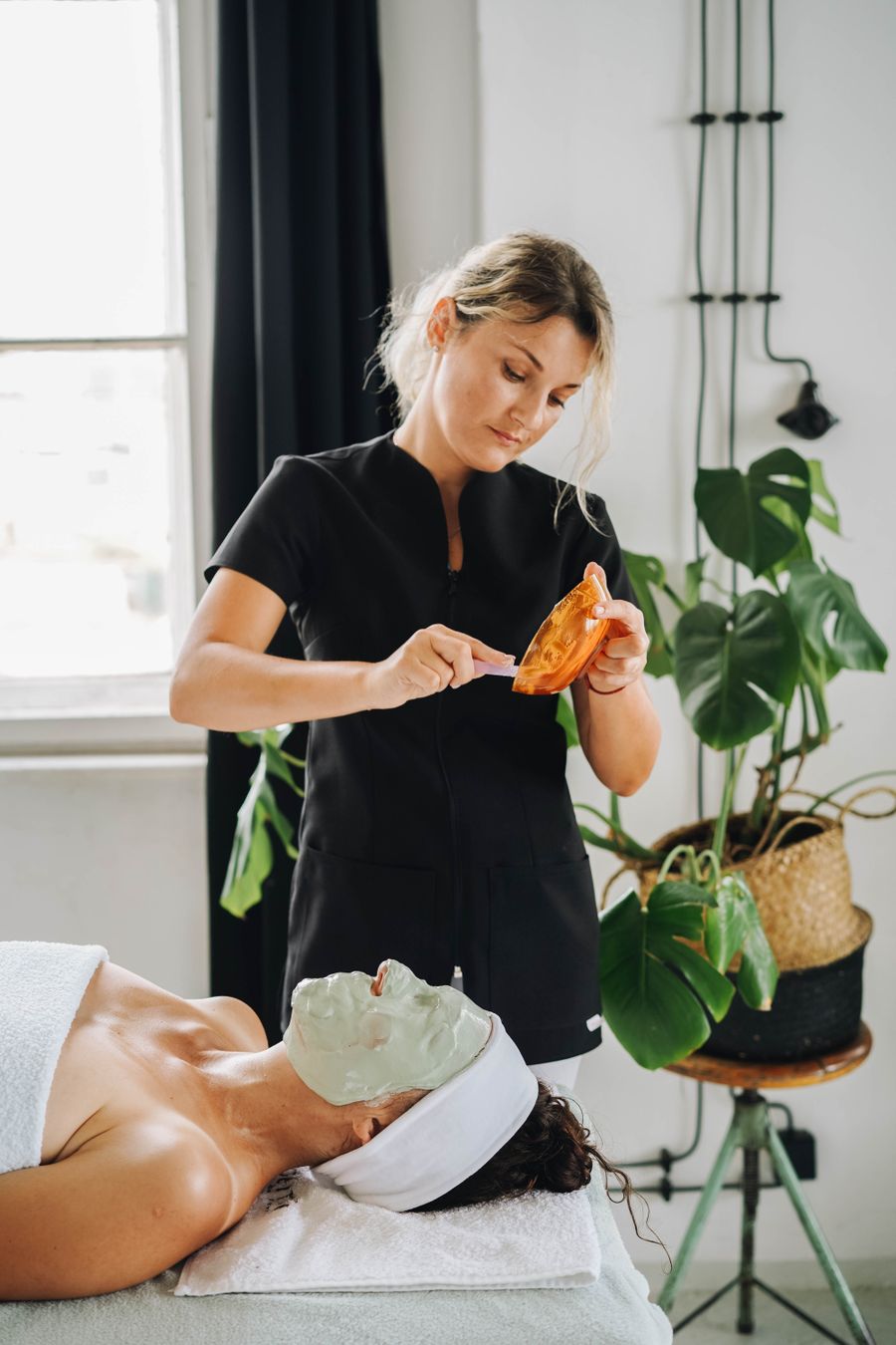 Esthetician applying a clay mask to a client's face