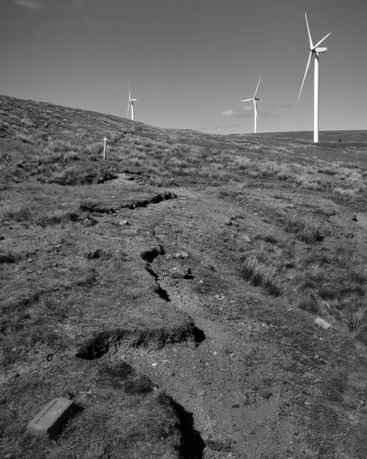 Black and white image of wind turbines on a hillside in West Yorkshire, UK.