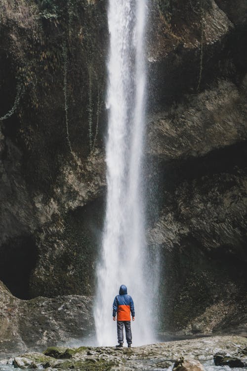 Photo of a Person Standing Near a Waterfall