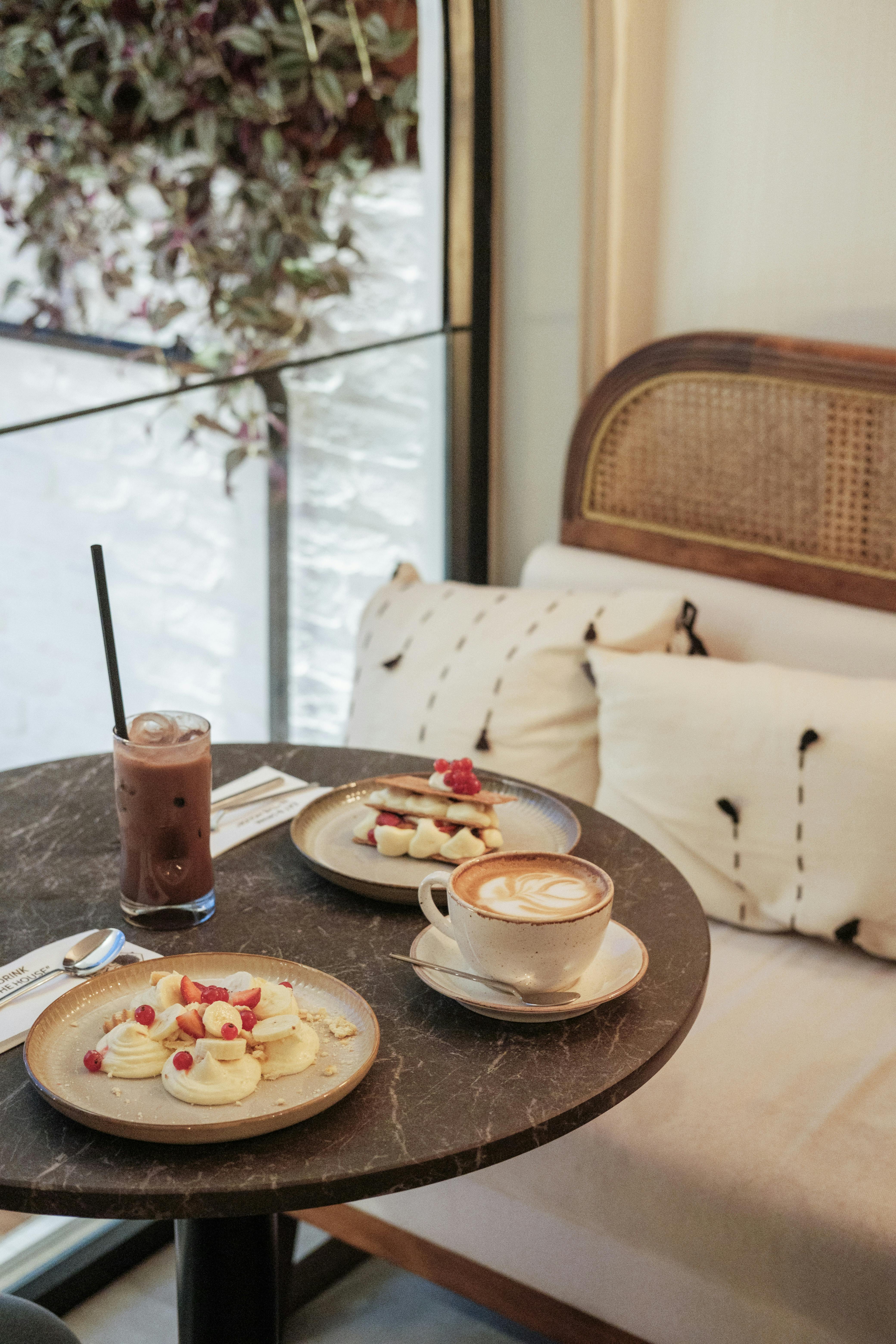Cozy cafe table setting with coffee and pastries by the window, perfect for breakfast lovers.
