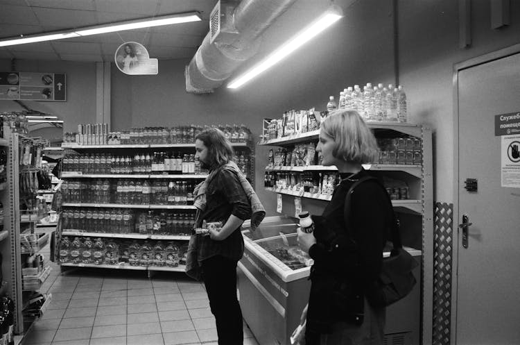 A Couple Looking At The Items On The Shelves Of A Grocery Store