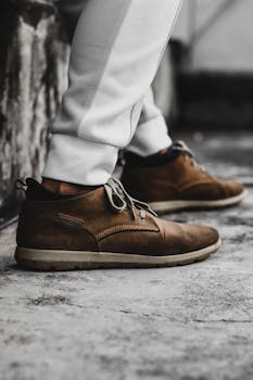 Close-up of brown leather shoes worn on a textured urban street surface in Dhaka.
