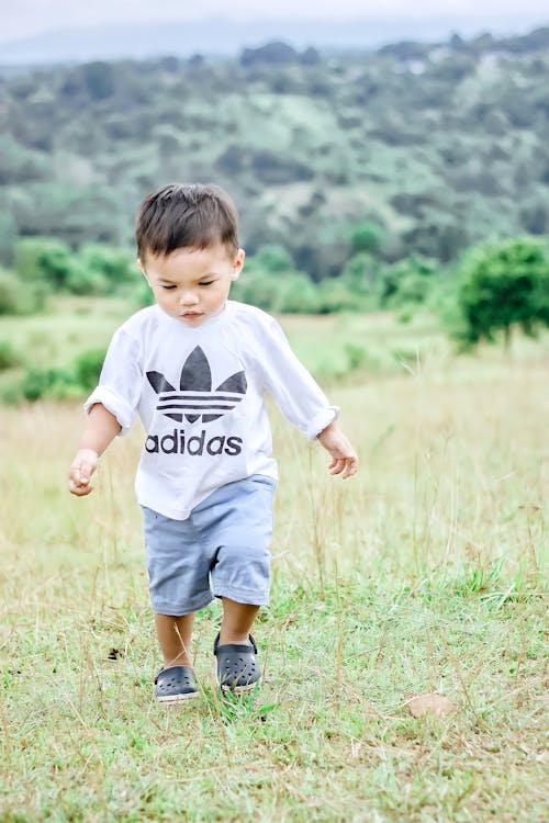 Cute Kid in a White Crew Neck Shirt Walking on the Grass