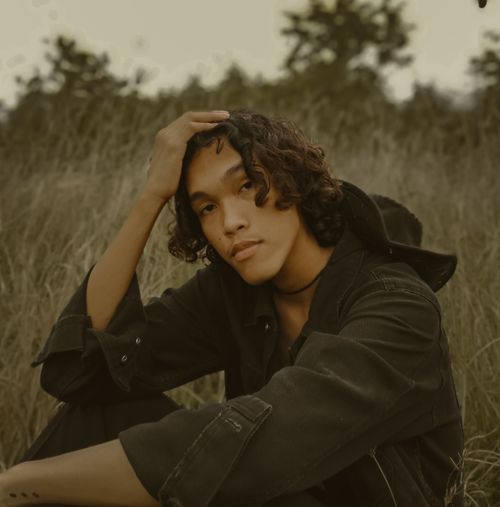 Free Fashion model in a grassy field, showcasing a serene and natural look with curly hair. Stock Photo