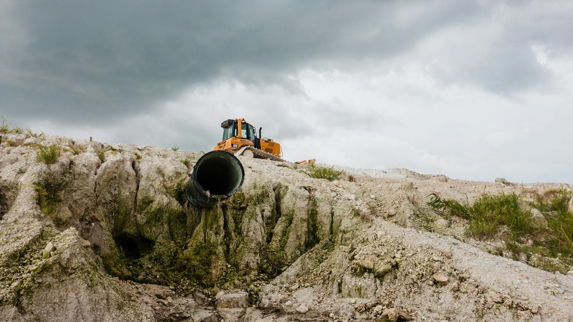 Excavator on a rocky cliff at Moss Point, Mississippi, with a stormy sky backdrop.