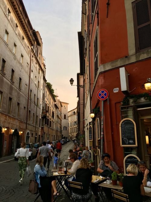 Free Bustling street with people dining and walking in historic Rome, capturing evening charm. Stock Photo