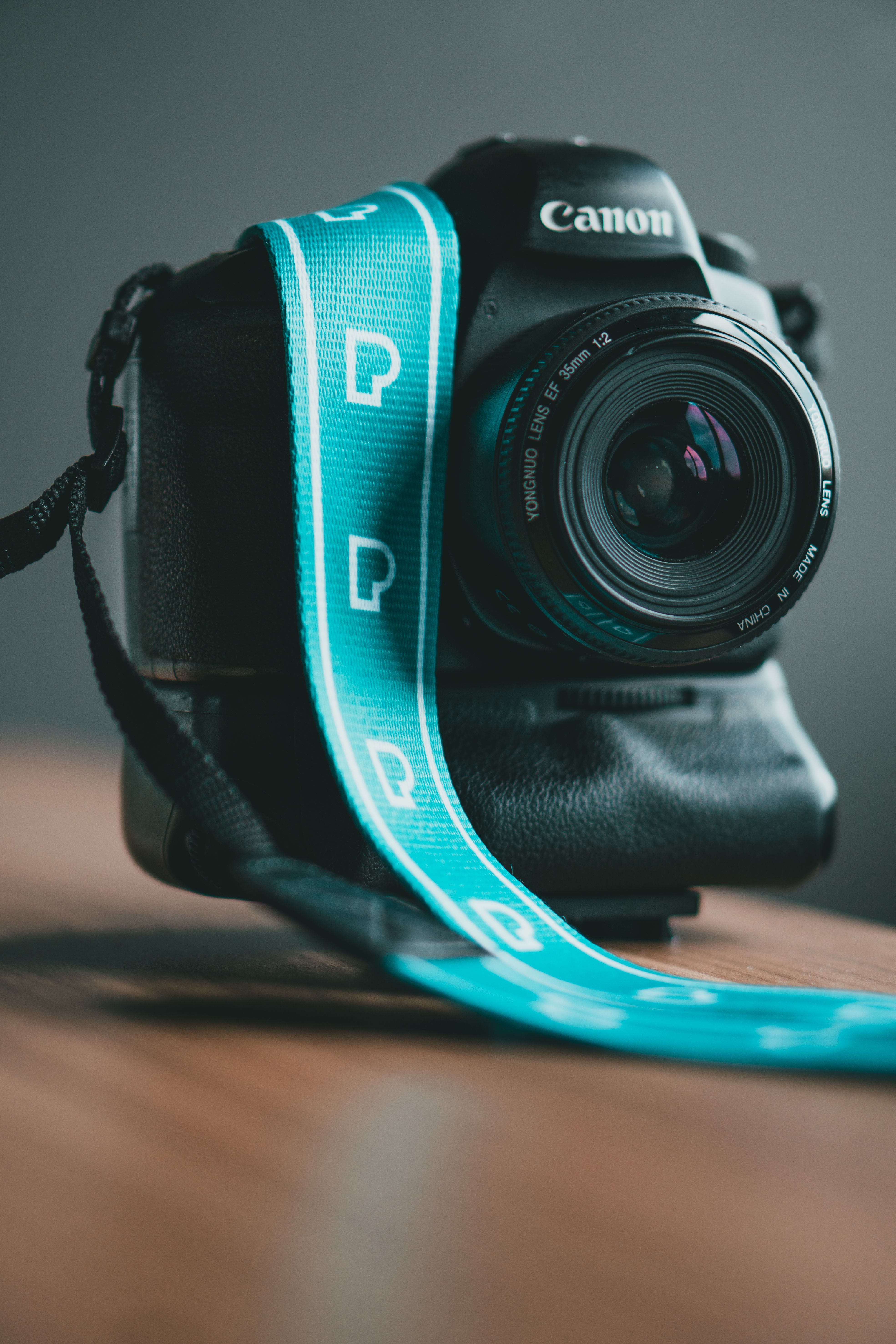 A detailed view of a DSLR camera with a blue strap, perfect for photography enthusiasts and professionals.