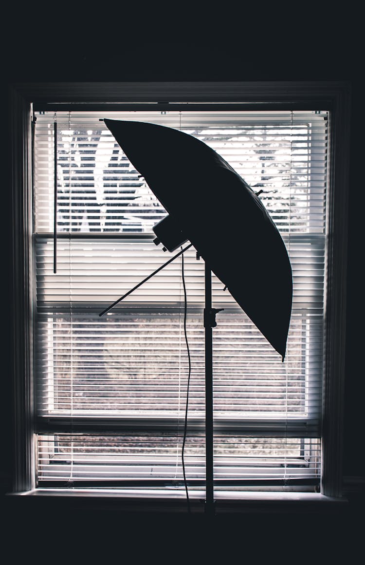 Silhouette Photo Of Studio Umbrella Near White Window Blinds Inside Room