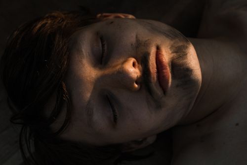 Free Close-up shot of a man with closed eyes and a dirty face in natural lighting. Stock Photo