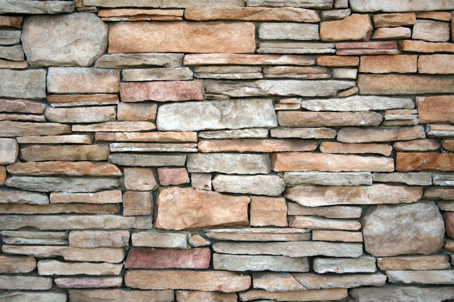 High-resolution image of a natural stone wall with various textures and earthy tones.