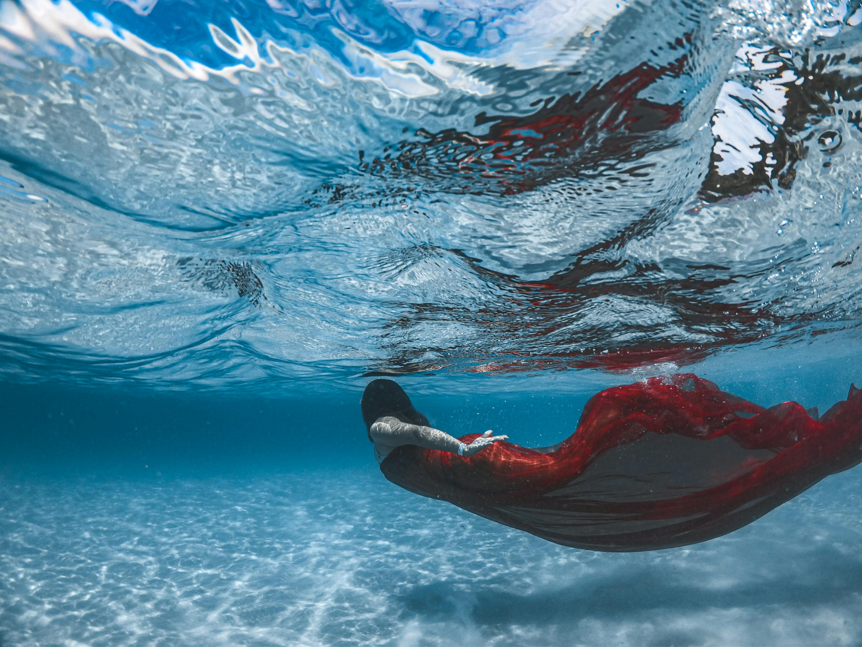 Person in Red and Black Wetsuit in Blue Water