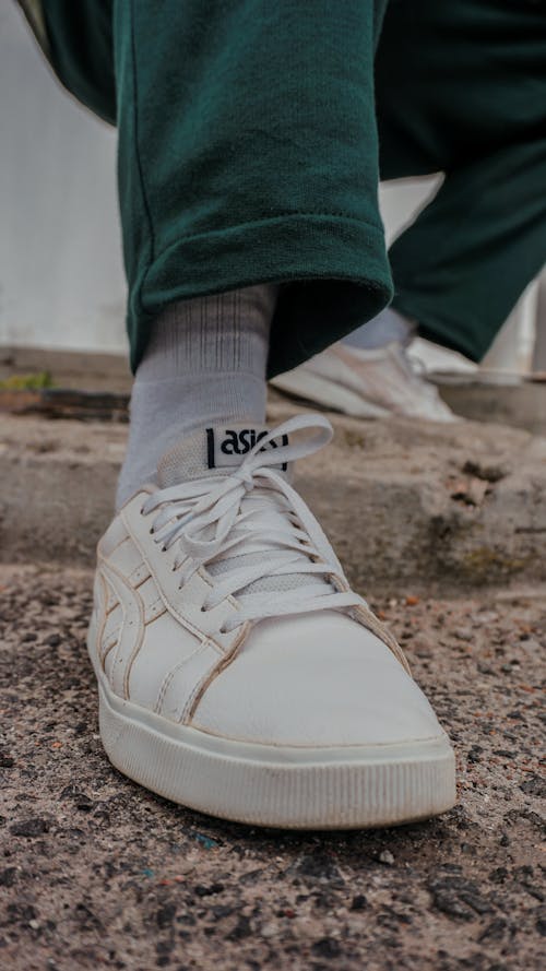 Close-Up Photo of White Sneakers on a Concrete Pavement