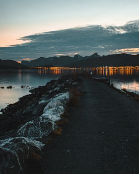 Beautiful coastal view of Tromsø with city lights reflecting on the water at twilight.