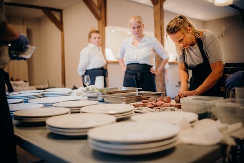 Woman in Gray Shirt Standing in Front of Table Preparing Food