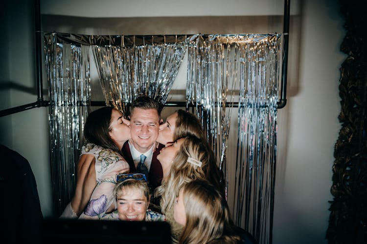 Women Kissing Smiling Man On Disco Background