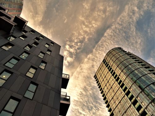 Free A low-angle view of modern skyscrapers with a dramatic sky backdrop, showcasing architectural design and urban perspective. Stock Photo