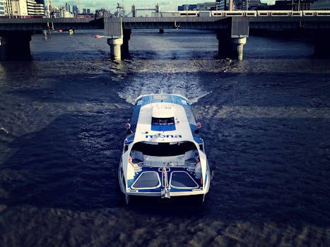 白天，高角度拍摄的渡轮在混凝土桥下的城市河流上行驶