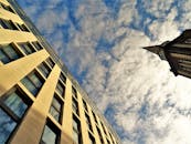 低角度视角下的现代建筑与教堂尖塔，映衬在多云的天空下