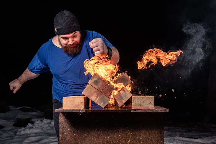 Strong Man Smashing Burning Logs With Fist