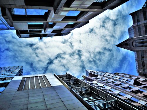 Free Low angle view of modern skyscrapers framing a dramatic cloudy sky, showcasing architectural design. Stock Photo
