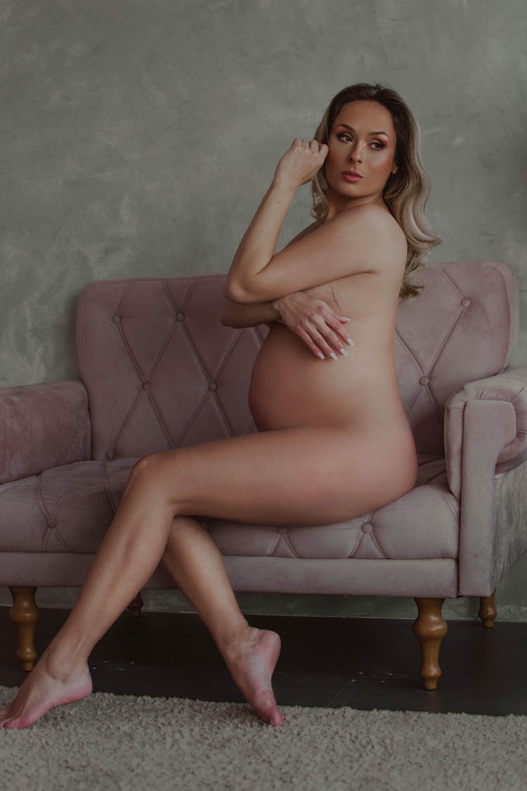 Naked Pregnant Woman Sitting On Pink Couch