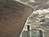 在阴云密布的天空映衬下，这座现代建筑结构勾勒出独特的城市天际线