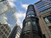 低角度拍摄的现代玻璃幕墙摩天大楼，映衬着蓝天白云