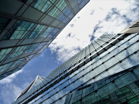 从低角度仰望，摩天大楼的反光玻璃外墙映衬着蓝天白云