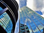 低角度视角下的现代玻璃建筑，窗户倒映着蓝天和云彩