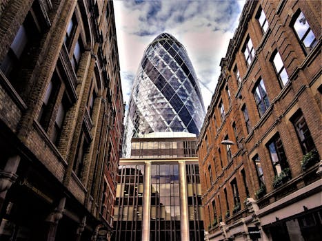 Stunning low-angle view of The Gherkin amidst historic buildings in London, showcasing architectural contrasts.