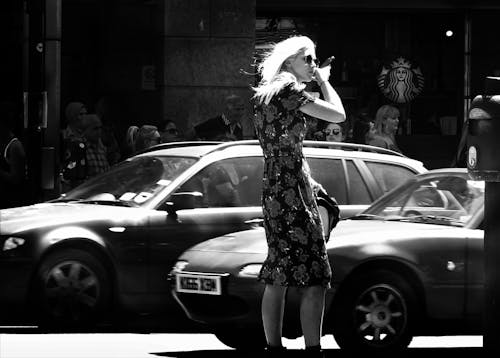 Woman Wearing Floral Short-sleeve Dress Standing Beside Car Grayscale Photo