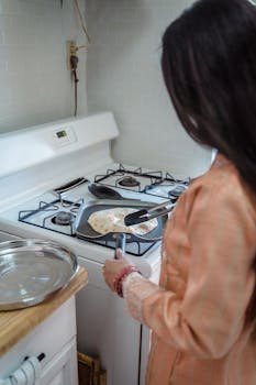 A woman in traditional attire cooking on a gas stove, focusing on healthy homemade food.