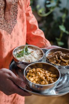 A traditional Indian meal served in metal bowls with rice, curry, and chickpeas.