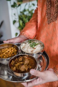 Indian meal of rice, chickpeas, and curry served in stainless steel bowls on a tray.