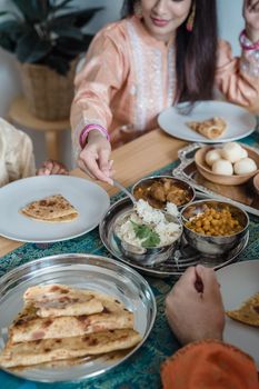 Enjoying Indian cuisine together with family at home, sharing naan, curry, and rice.