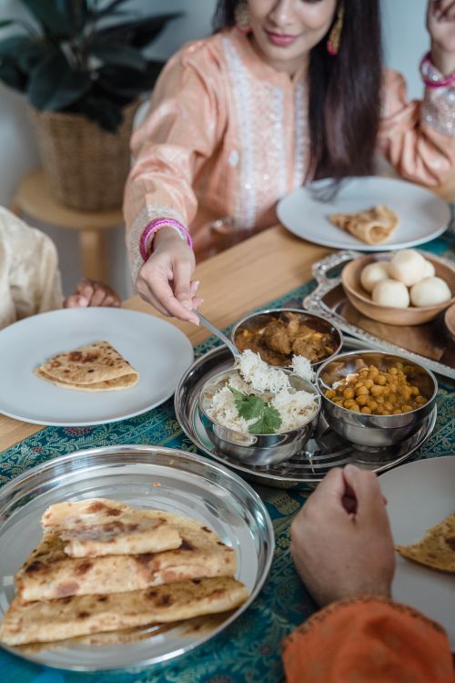 Free Enjoying Indian cuisine together with family at home, sharing naan, curry, and rice. Stock Photo