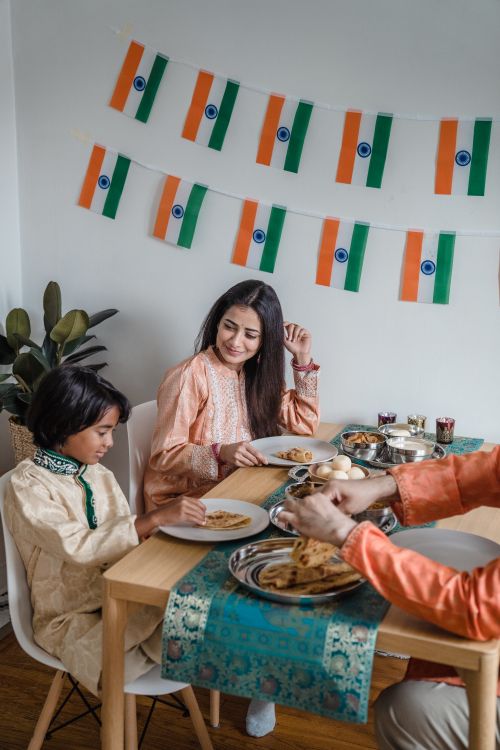 Free A joyful family gathering enjoying traditional Indian cuisine at a decorated dining table indoors. Stock Photo