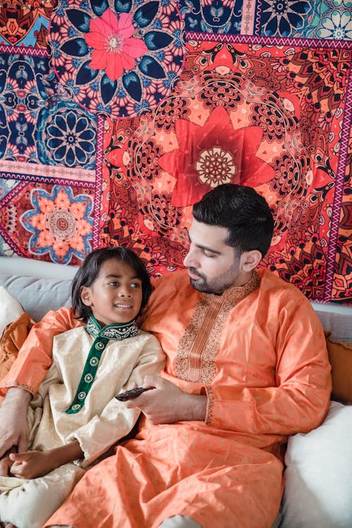 Man in Orange Dress Shirt Beside Boy in Green Shirt