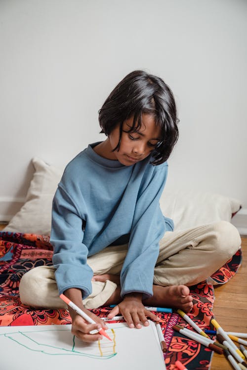 Woman in Blue Sweater and Brown Pants Sitting on Bed