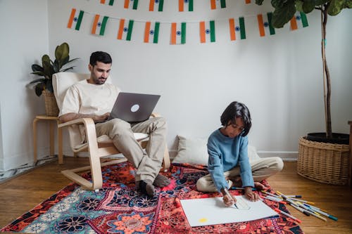 Man and Woman Sitting on Couch Using Macbook