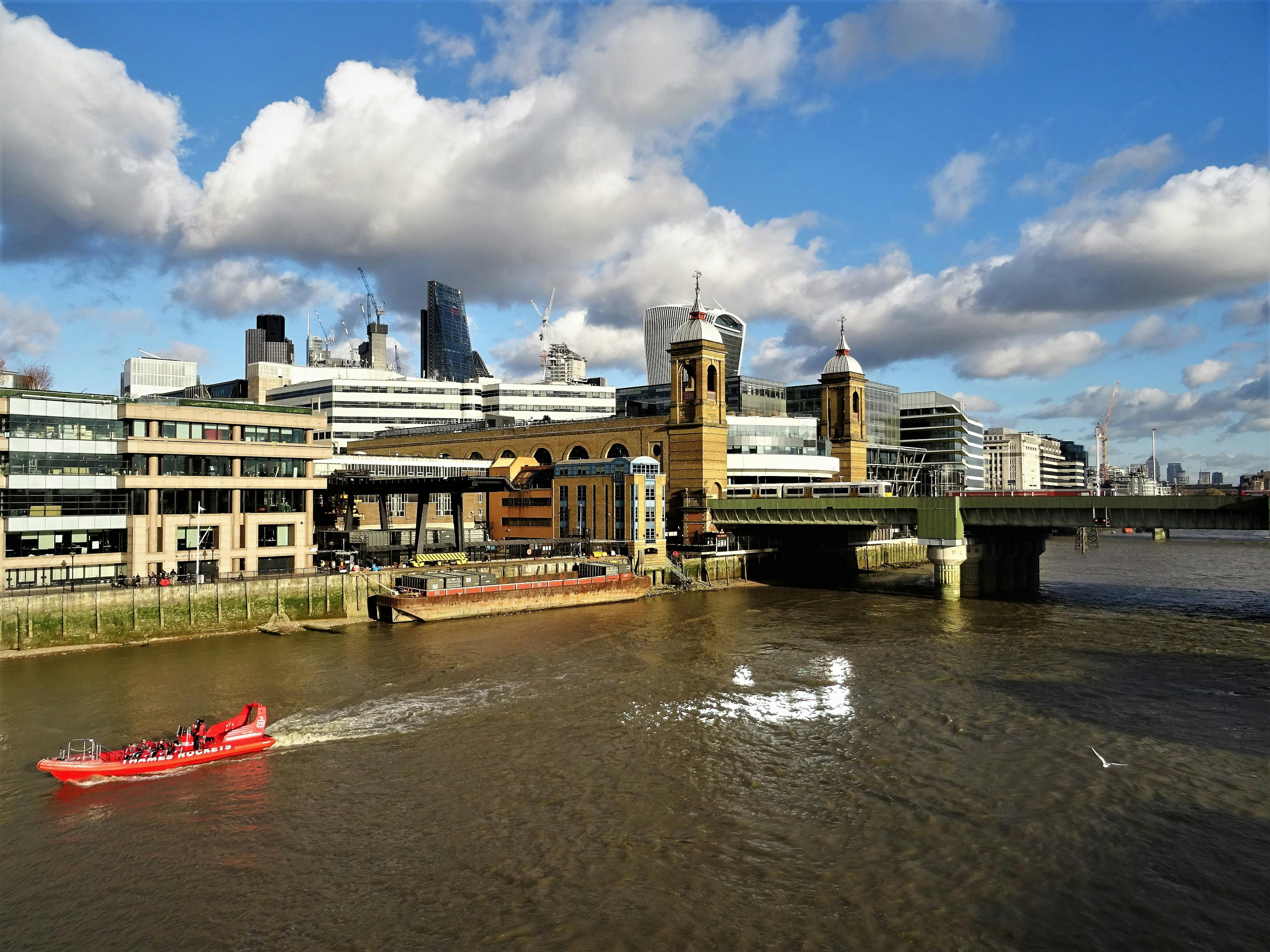 伦敦的城市景观令人惊叹，包括著名建筑、泰晤士河上的红船和引人注目的云层