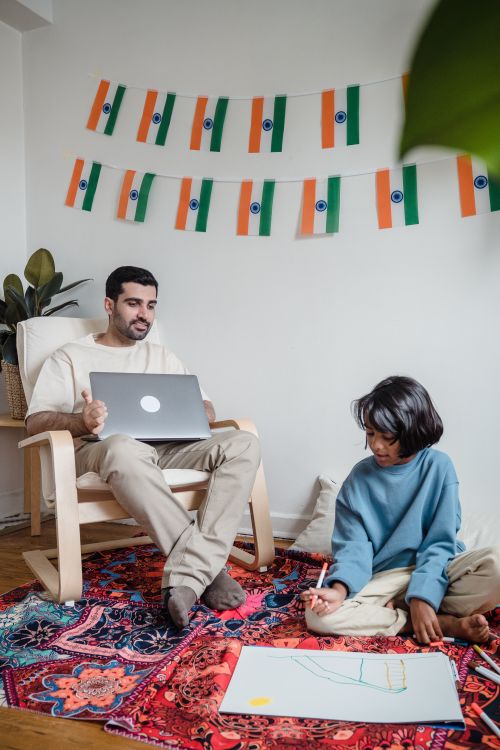 Free Father and child enjoying quality time with laptop and drawing at home. Stock Photo