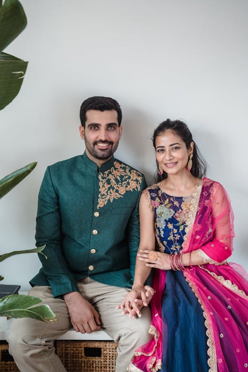 Man in Green Suit Beside Woman in Purple and Yellow Dress