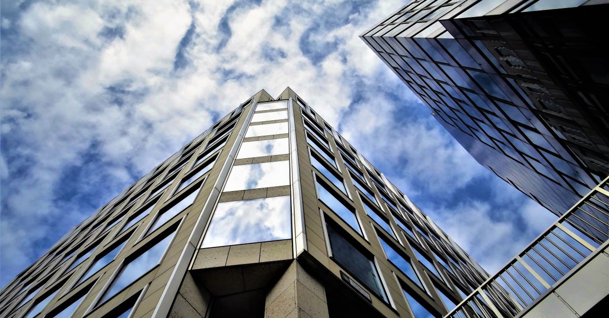 Low angle view of modern skyscraper with glass facade reflecting the sky.